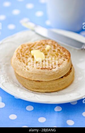 Hot buttered crumpets on white plate - Stock Photo