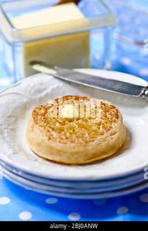 Hot buttered crumpets on white plate - Stock Photo