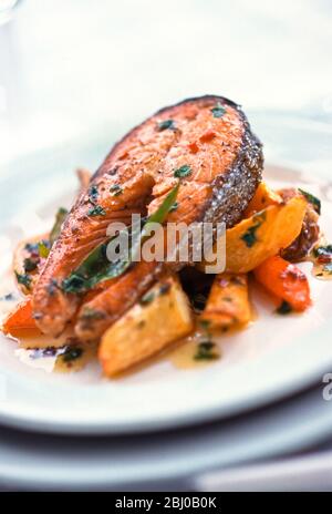 Grilled salmon steak on mixed roast root vegetables - Stock Photo