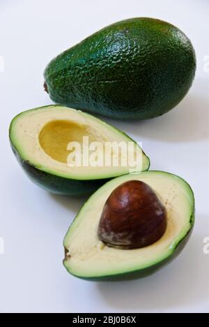 Whole and cut fresh avocado pear on white background - Stock Photo
