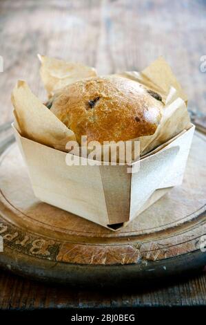 Small 'designer' style loaf on old fashioned wooden breadboard - Stock Photo