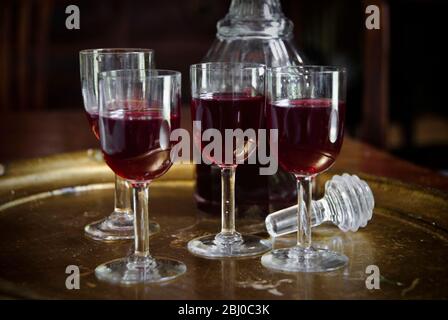 A tray of glasses of sloe gin with unstoppered decanter. - Stock Photo