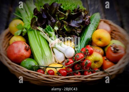 Basket of fresh fruit and vegetables on red surface - Stock Photo
