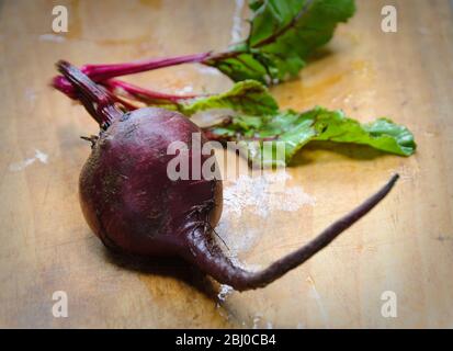 Whole fresh raw beetroots on wooden board - Stock Photo