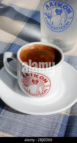 Little cup of strong Greek coffee, with glass of water on table of beach restaurant in southern Cyprus - Stock Photo