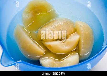 Canned Bartlett pears opened and turned into a blue bowl - Stock Photo