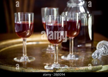 A tray of glasses of sloe gin with unstoppered decanter. - Stock Photo