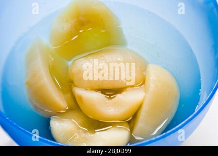 Canned Bartlett pears opened and turned into a blue bowl - Stock Photo