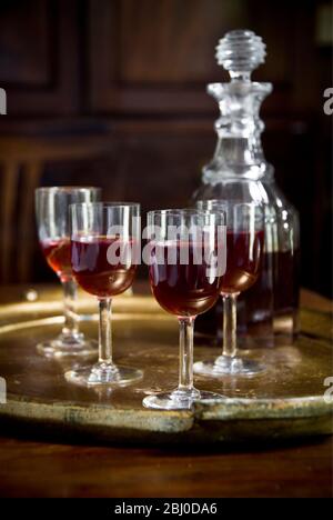 A tray of glasses of sloe gin with unstoppered decanter. - Stock Photo