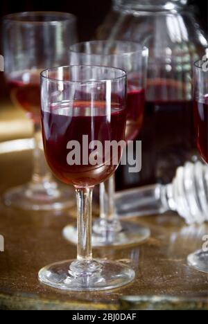 A tray of glasses of sloe gin with unstoppered decanter. - Stock Photo