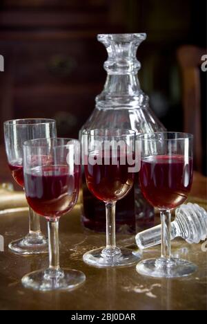 A tray of glasses of sloe gin with unstoppered decanter. - Stock Photo