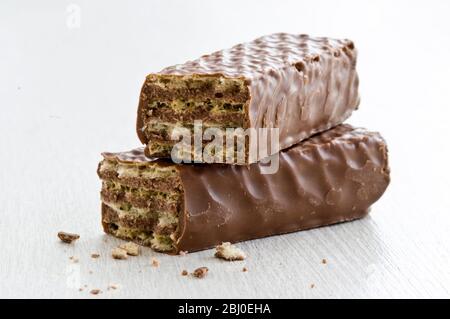 Chocolate wafer bar, broken in two, on white surface. - Stock Photo