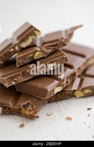 Pile of broken pieces of nut mik chocolate bar on white surface. - Stock Photo