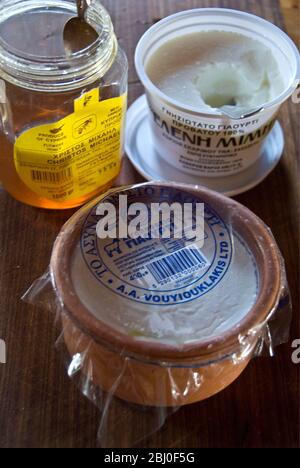 Plastic carton of Greek set cow's milk yoghurt and pottery dish of sheeps milk yoghurt , with Cypriot honey, on kitchen counter in Cypriot house - Stock Photo