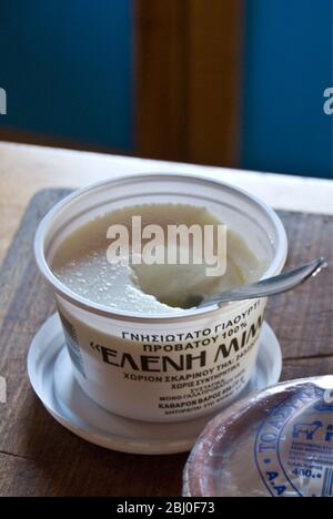 Plastic carton of Greek set cow's milk yoghurt on kitchen counter in Cypriot house - Stock Photo