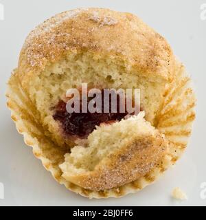 Muffin with sugary top filled with jam (jelly), broken open to show filling. A muffin masqerading as a doughnut! - Stock Photo