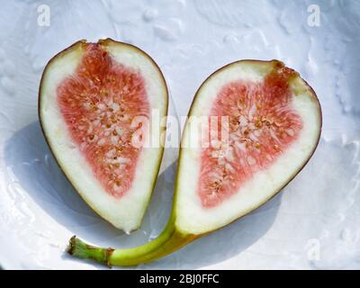 Halved ripe fig on white plate - Stock Photo