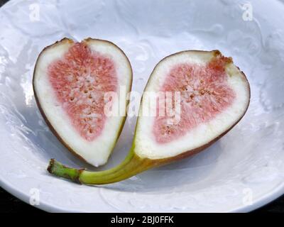 Halved ripe fig on white plate - Stock Photo