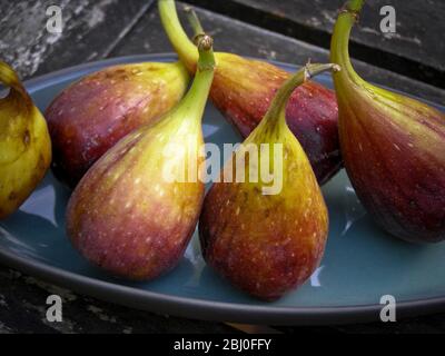 Fresh figs on pottery plate outside on garden table - Stock Photo
