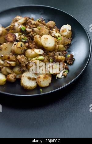 Dish of fried potatoes, sauteed with anchovies, spring onions and breadcrumbs. - Stock Photo