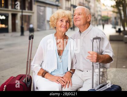 Happy loving mature spouses enjoying joint vacation sitting on bench Stock Photo