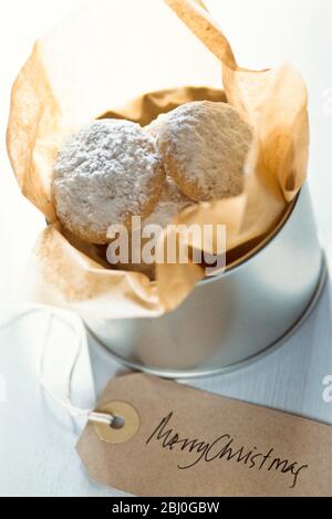Tin of homemade cookies wrapped as Christmas gift - Stock Photo