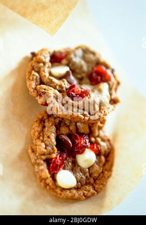 Cranberry and peanut and chocolate chip cookies on greaseproof paper - Stock Photo