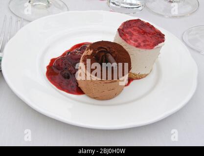 Chocolate and vanilla mousses with sumer fruits coulis - dessert at wedding reception - Stock Photo