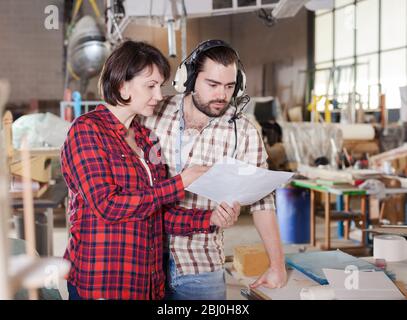 Team of aircraft enthusiasts working in workshop on creating of airplane models, checking design in drawings Stock Photo