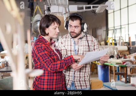 Team of aircraft enthusiasts working in workshop on creating of airplane models, checking design in drawings Stock Photo