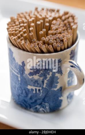 SIngle ended toothpicks in pretty old 'Adams' 'Landscape' cup. Putting antique and junshop finds to practical use. - Stock Photo