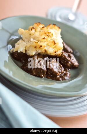 Braised beef with grilled cheesy mashed potatoes, on green plate. - Stock Photo