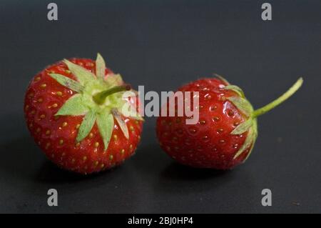 Two strawberries on a black plate - Stock Photo
