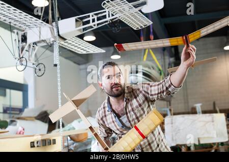 Cheerful male aircraft enthusiast holding sports airplane models in workshop Stock Photo