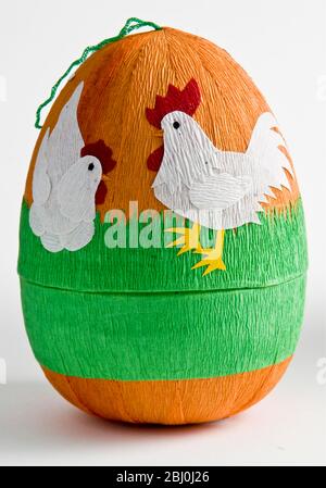 Decorative paper box shaped as Easter eggs with paper shapes of chickens stuck on with coloured crepe paper - Stock Photo