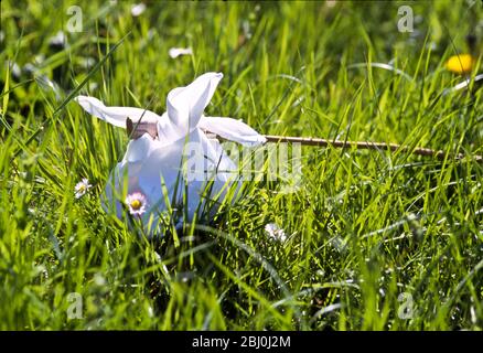 Picnic tied up in a handkerchief on a stick sitting in long grass with daisies and dandelions. - Stock Photo