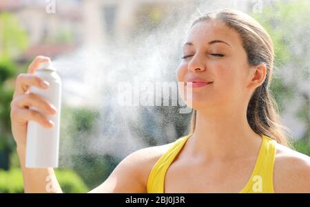 Young woman spraying Thermal Water on her face outside. Thermal water used for skin care, fix makeup, help skin irritation, redness and insect bites. Stock Photo