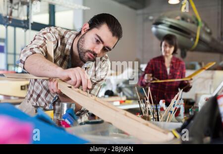 Nice male aircraft enthusiast working in workshop on creating of airplane models Stock Photo