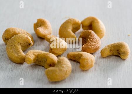 Slated cashew nuts in small pile in white surface - Stock Photo
