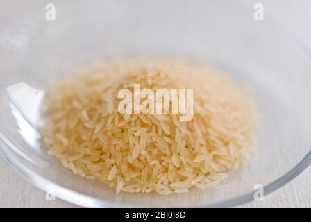 Small pile of natural longgrain rice on white background - Stock Photo