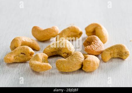 Slated cashew nuts in small pile in white surface - Stock Photo
