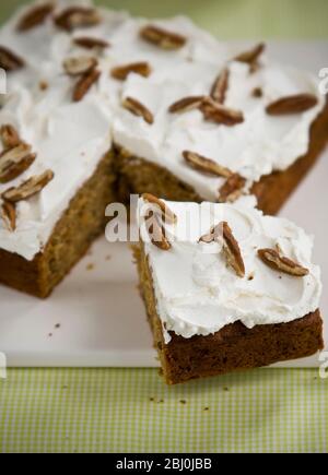 Passion cake with buttercream tpping with slivers of pecan nuts - Stock Photo