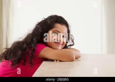 Portrait of a young girl sitting and smiling at home. (Children) Stock Photo