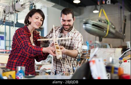Team of adult aircraft enthusiasts working in workshop on creating of airplane models Stock Photo