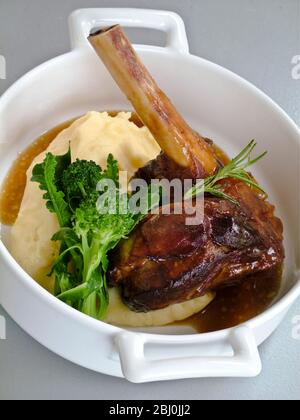 Slow cooked braised lamb shanks with rosemary, served with mashed potato and broccoli - Stock Photo