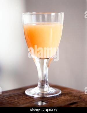 Grapefruit juice in stemmed glass on corner of table - Stock Photo