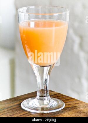 Grapefruit juice in stemmed glass on corner of table - Stock Photo