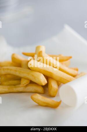 Deep fried potato chips on greaseproof paper - Stock Photo