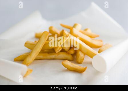 Pile of french fries on greaseproof paper - Stock Photo