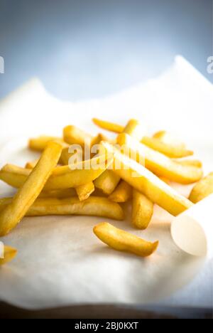 Pile of french fries on greaseproof paper - Stock Photo
